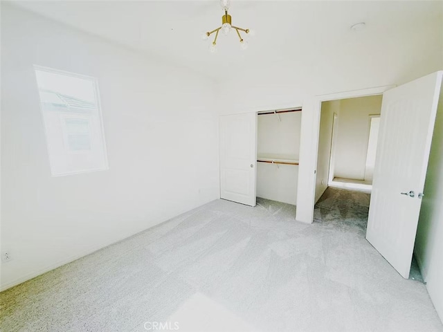 unfurnished bedroom with an inviting chandelier, light carpet, and a closet