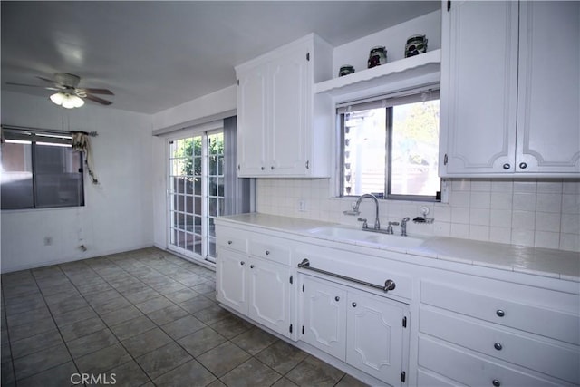 kitchen featuring a sink, light countertops, white cabinets, and tasteful backsplash