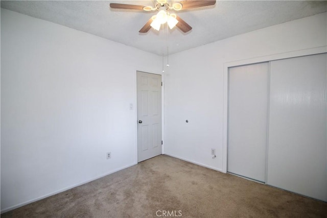 unfurnished bedroom with a closet, carpet, and ceiling fan