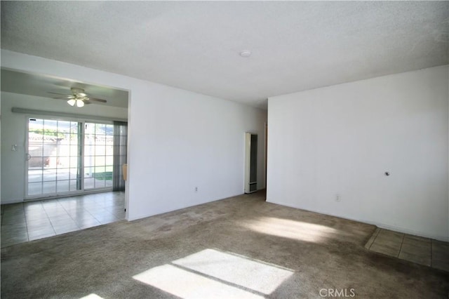 carpeted spare room with a ceiling fan and tile patterned floors