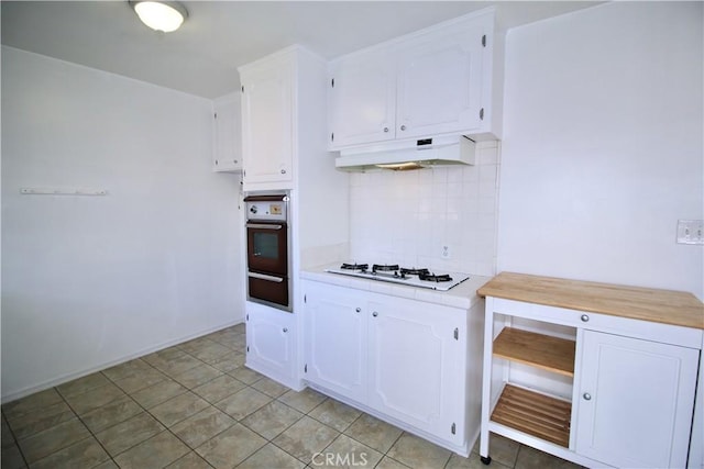 kitchen featuring decorative backsplash, wall oven, white cabinets, a warming drawer, and under cabinet range hood