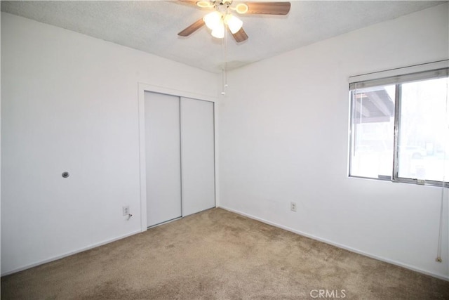 unfurnished bedroom featuring a ceiling fan, carpet, and a closet