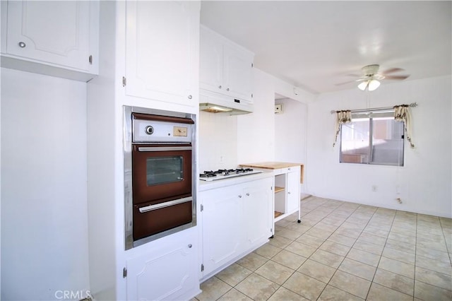 kitchen featuring oven, white cabinetry, white gas stovetop, under cabinet range hood, and a warming drawer