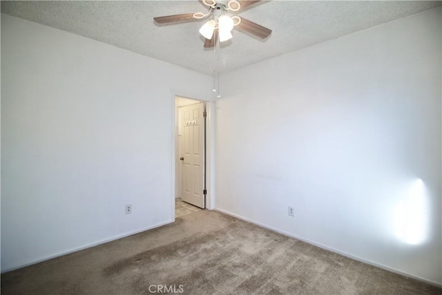 empty room with carpet floors, a ceiling fan, a textured ceiling, and baseboards