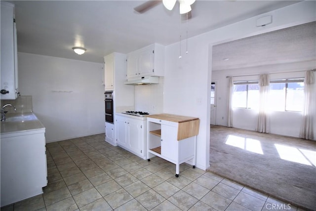kitchen with a sink, backsplash, black oven, and white cabinetry