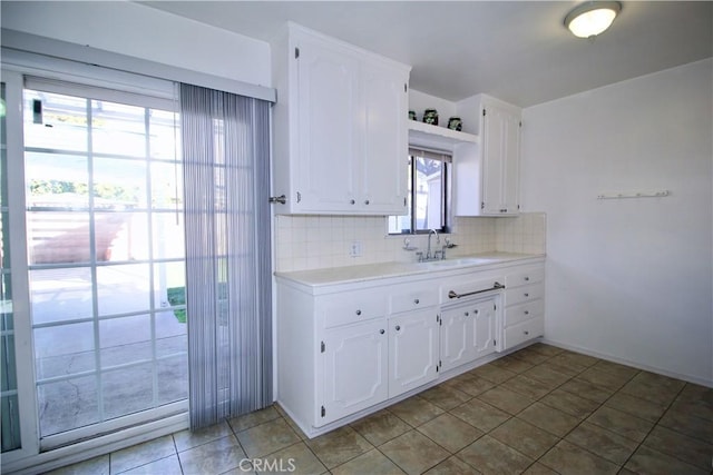 kitchen with open shelves, a sink, light countertops, white cabinetry, and decorative backsplash