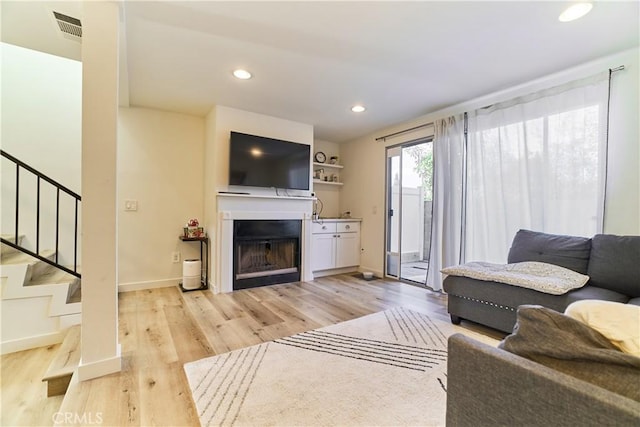 living area featuring visible vents, light wood-style floors, baseboards, stairway, and recessed lighting
