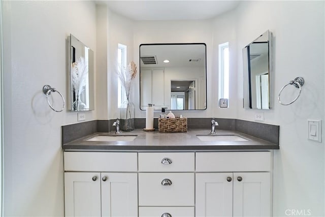 bathroom featuring visible vents, a sink, and double vanity