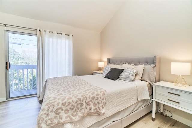 bedroom featuring access to outside, vaulted ceiling, light wood finished floors, and multiple windows