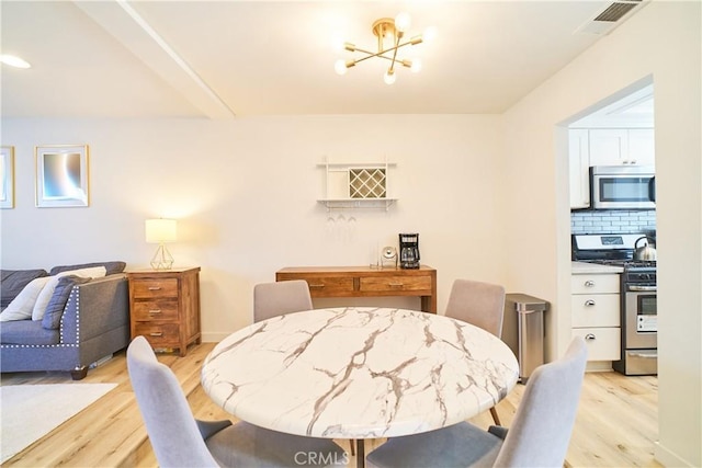 dining room featuring an inviting chandelier, visible vents, and light wood-type flooring