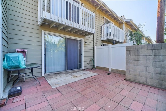 view of patio featuring fence and a balcony