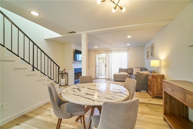 dining space featuring light wood finished floors, a fireplace, recessed lighting, visible vents, and stairway