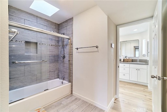 full bathroom with vanity, wood finished floors, baseboards, combined bath / shower with glass door, and a skylight