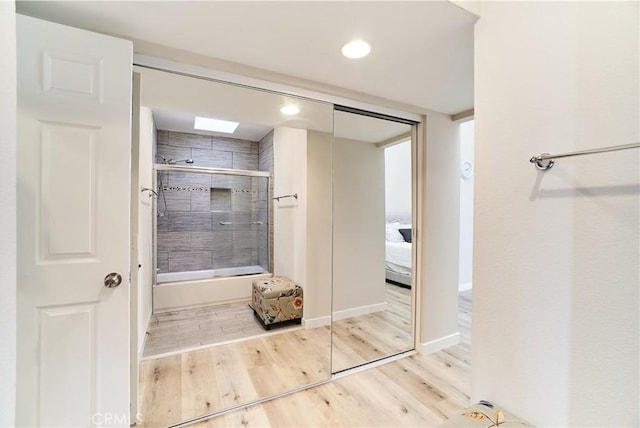 ensuite bathroom featuring ensuite bath, enclosed tub / shower combo, recessed lighting, baseboards, and wood finished floors