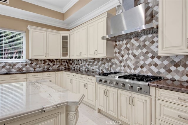 kitchen with wall chimney range hood, crown molding, tasteful backsplash, dark stone countertops, and stainless steel gas stovetop