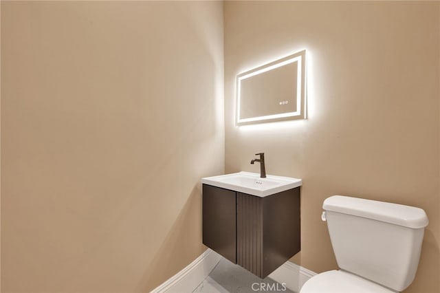 bathroom with baseboards, vanity, and toilet