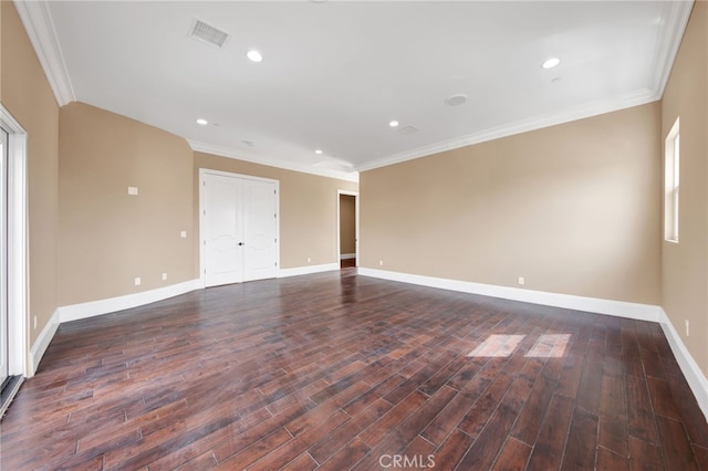 spare room featuring visible vents, ornamental molding, baseboards, and dark wood finished floors