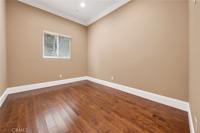 spare room with crown molding, dark wood-style flooring, and baseboards