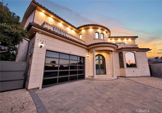 mediterranean / spanish-style home with french doors, a gate, decorative driveway, fence, and an attached garage