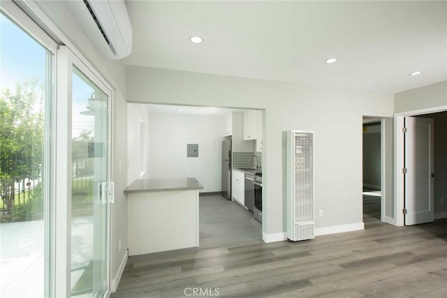 5459 Carlin St, Los Angeles, CA 90016 - unfurnished living room featuring light wood-type flooring, a wall mounted air conditioner, a sink, recessed lighting, and a heating unit