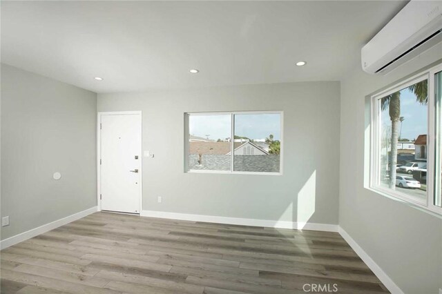 5459 Carlin St, Los Angeles, CA 90016 - unfurnished room with a healthy amount of sunlight, a wall unit AC, and light wood finished floors