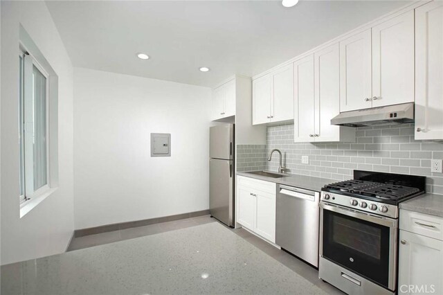 5459 Carlin St, Los Angeles, CA 90016 - kitchen with under cabinet range hood, white cabinets, a sink, appliances with stainless steel finishes, and backsplash