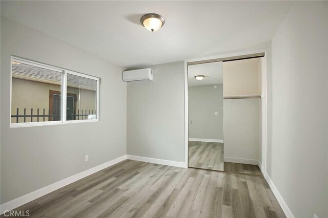 5459 Carlin St, Los Angeles, CA 90016 - unfurnished bedroom with baseboards, a wall mounted air conditioner, a closet, and wood finished floors