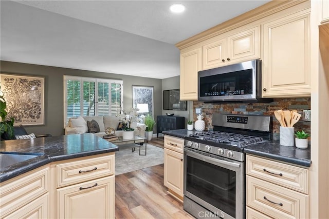 21340 Via Del Puma, Yorba Linda, CA 92887 - kitchen featuring appliances with stainless steel finishes, cream cabinetry, dark countertops, light wood-style flooring, and tasteful backsplash