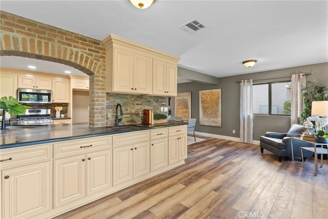 21340 Via Del Puma, Yorba Linda, CA 92887 - kitchen with cream cabinetry, stainless steel appliances, dark countertops, and decorative backsplash
