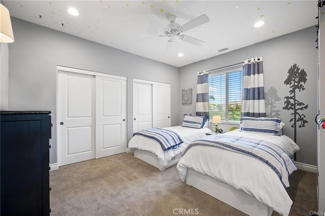 carpeted bedroom featuring two closets, recessed lighting, ceiling fan, and visible vents