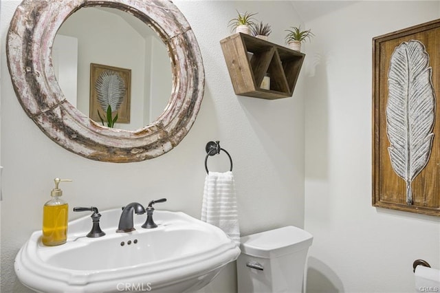 half bathroom featuring toilet and a sink