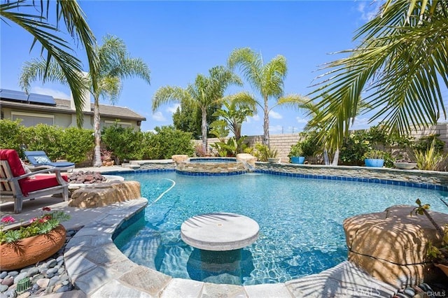 view of swimming pool with fence and a pool with connected hot tub