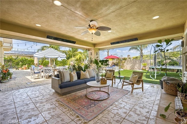 view of patio / terrace with ceiling fan, fence, outdoor dining space, and a trampoline