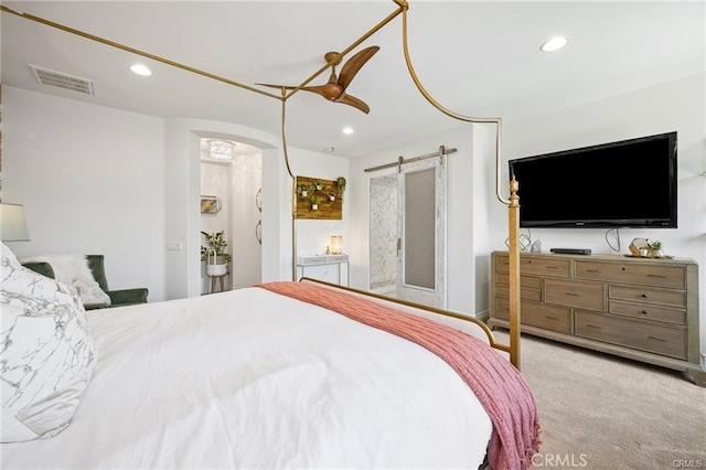 carpeted bedroom featuring ceiling fan, a barn door, arched walkways, recessed lighting, and visible vents