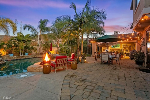 view of patio / terrace with outdoor dining space, an outdoor fire pit, and an outdoor pool