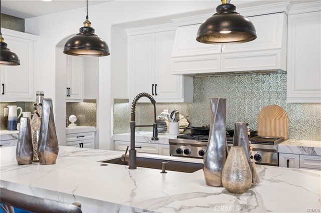 kitchen with white cabinets, light stone countertops, pendant lighting, and decorative backsplash