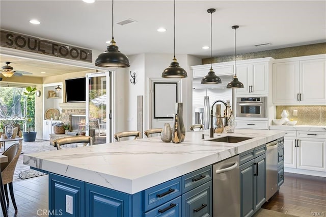 kitchen with a sink, appliances with stainless steel finishes, white cabinets, and backsplash