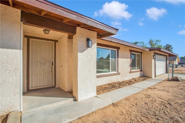 property entrance featuring an attached garage and stucco siding