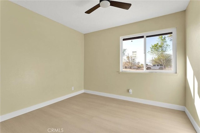 empty room with baseboards, a ceiling fan, and light wood-type flooring