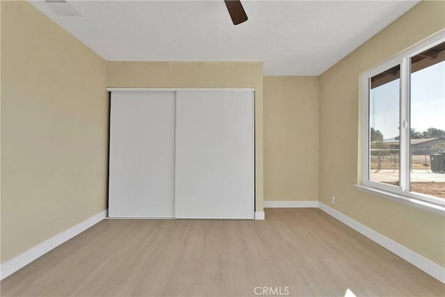 unfurnished bedroom featuring baseboards, wood finished floors, and a closet