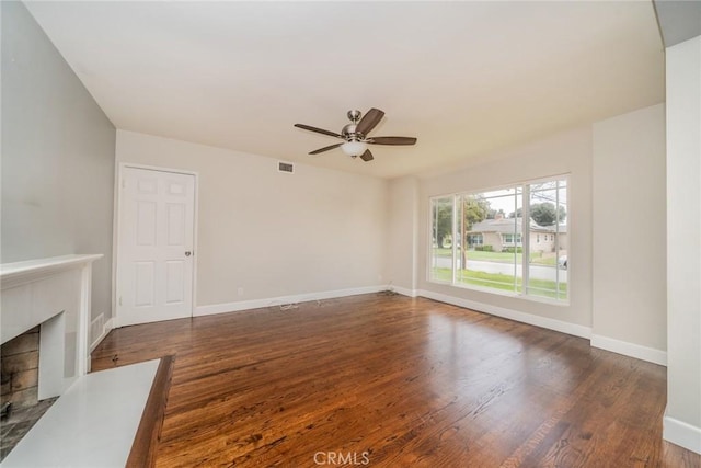 unfurnished living room featuring visible vents, wood finished floors, a fireplace, baseboards, and ceiling fan