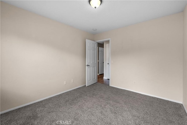 empty room featuring baseboards and carpet