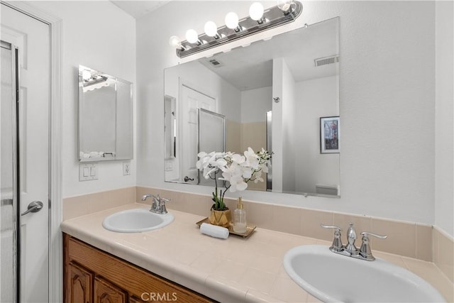 full bathroom with double vanity, visible vents, and a sink