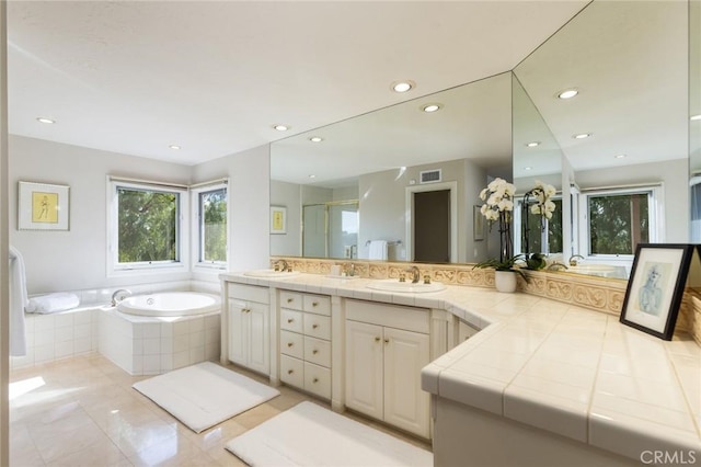 bathroom featuring visible vents, a sink, a garden tub, and double vanity
