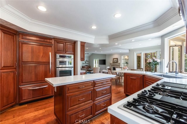 kitchen with light countertops, ornamental molding, a sink, and stovetop with downdraft