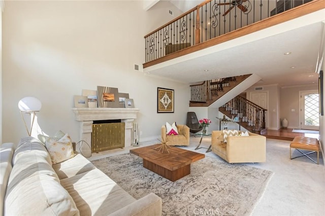 living room featuring visible vents, ornamental molding, stairs, a towering ceiling, and a fireplace