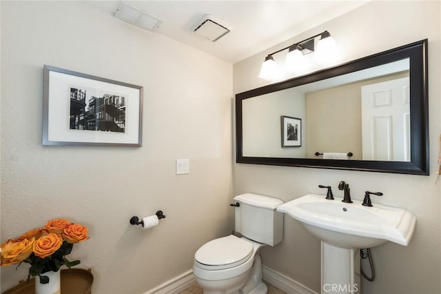 half bathroom with toilet, baseboards, and visible vents