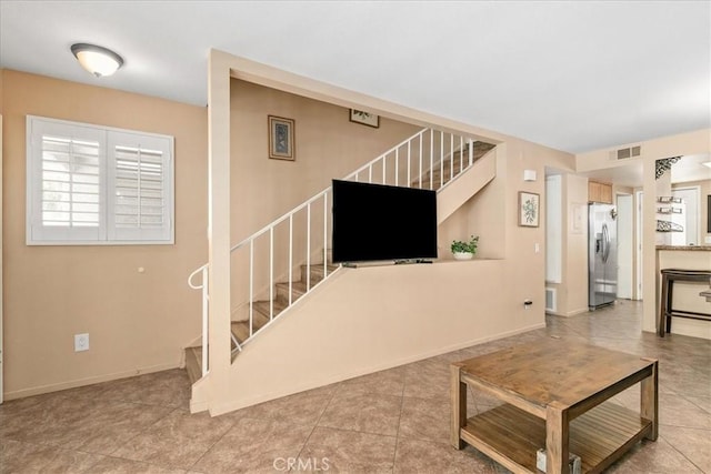 living area with tile patterned floors, baseboards, stairs, and visible vents