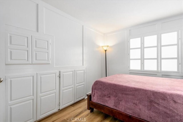 bedroom with light wood-style floors and a decorative wall