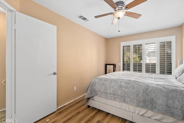 bedroom featuring baseboards, ceiling fan, wood finished floors, and visible vents